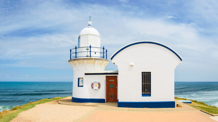 Port Macquarie Lighthouse, Australian coast with white lighthouse on green cliff top, seaside landscape with blue sea on summer sunny day.