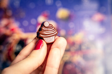Christmas advent calendar chocolate cupcake in a hand, December, blue festive bokeh bg