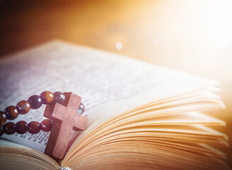 rays of divine light fall on an open book with a religious cross