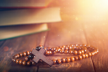 religious rosaries on the background of books with sacred teachings and magical light. the concept...