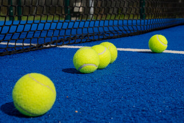 five paddle tennis balls close to the net of a paddle tennis court