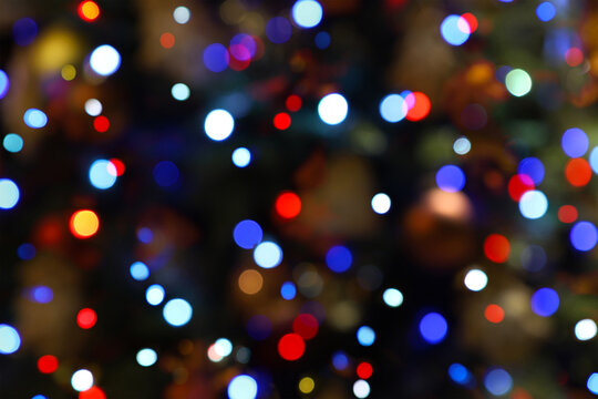 Colorful bokeh lights - big, small, blue, red. Abstract blurred Christmas tree garland lights background. Holiday New Year illumination and decoration concept. Defocused image.