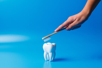 A woman brushes her teeth with an eco-friendly toothbrush. tooth on a blue background. Prevention...