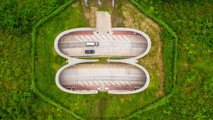 Aerial view of wildlife overpass over highway,  new road with tunnel in green summer mountains.