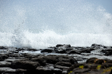 Powerful ocean waves crashing with violence on rocks. The sea meets the shore on the tropical island of Kauai, Hawaii during a storm with high wind. 