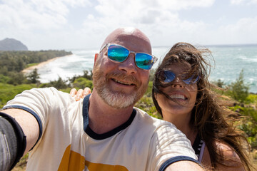Happy middle aged couple together on vacation at ocean beach. The man and woman are smiling for a selfie overlooking the sea. 