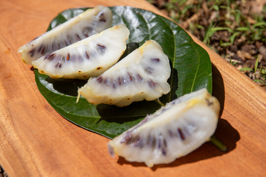 Fresh sliced noni fruit on a cutting board. The fruit has a pungent aroma like stinky cheese. 