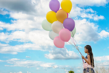 Cheerful beauty woman holding balloons relax sitting under big tree in green park with happiness. Woman Hands holding vibrant air balloons play on birthday party happy time summer on sunshine outdoor