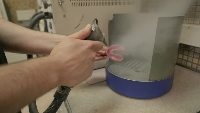 Using the sandblaster to clean the dirt from the gum model dental appliance. Tool cleaning the part of dental training appliance. Device cleaning the dust from the dental practice appliance
