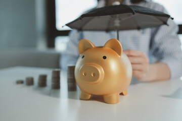 The financial worker held out a piggy bank, An accountant holds an umbrella over a piggy bank,...