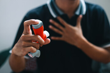 Man holding asthma inhaler for relief asthma attack. - obrazy, fototapety, plakaty