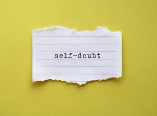 Torn note on yellow background with text  Self-doubt - means lacking of confidence or have a...
