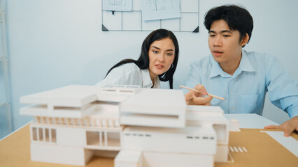 Closeup of skilled architecture engineer team measure and decide house model while working together...