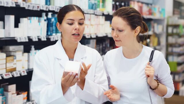 In cosmetic department of pharmacy, open-eyed female buyer listens to pharmacist s consultation and surprised. Visitor pleasantly surprised by advice of competent pharmacist