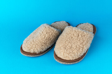 Comfortable beige slippers on a blue background.