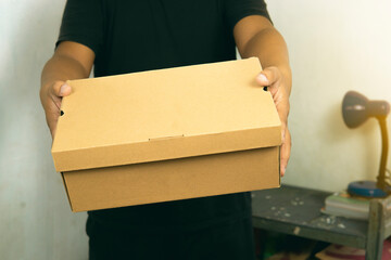 Male hand holding a small cardboard box. packaging and shipping concept