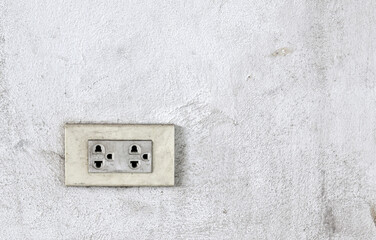 dirty electric outlet on grimy rough white concrete wall