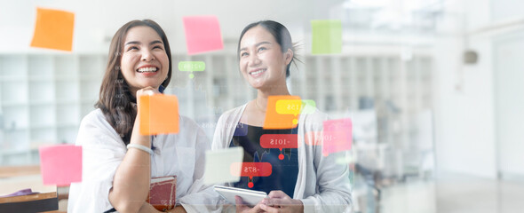 Creative business woman brainstorming using sticky notes on glass wall in office.