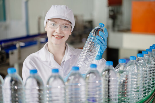 Portrait smiling young caucasian women worker with drink bottles work at factory production line drinking water plant quality control checking.