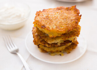Potato pancakes with sour cream on white plate