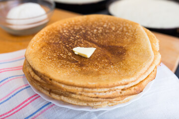 Freshly baked hot cereal pancakes on plate and pans during cooking