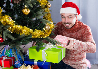 Man wearing Santa puts gifts under the Christmas tree
