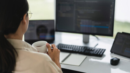 Developer programmer drinking coffee and checking code on monitor for programming to developing web