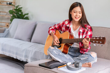 Hobby concept, Young woman sit on couch to singing and playing acoustic guitar after learning music