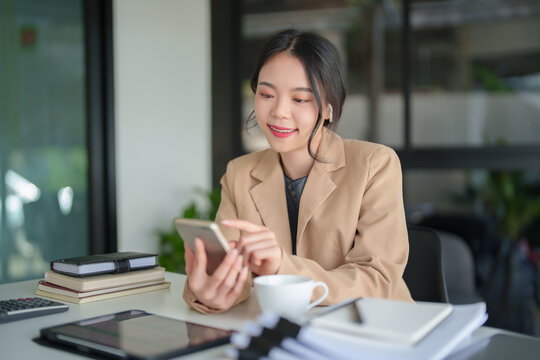 Businesswomen wearing bluetooth headphones and using smartphone to meeting on video call about financial and investment data of new business while discussion management about new startup project