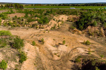 Overgrown exploratory sand pit in a field, soil removed to layers of sand