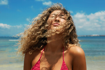 Beautiful happy woman on the beach. Smiling girl in Bikini near sea. Curty Hairstyle