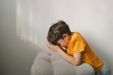 A boy in an orange T-shirt prays at home. Reading the Holy Bible. Concept for faith, spirituality and religion. Peace, hope.