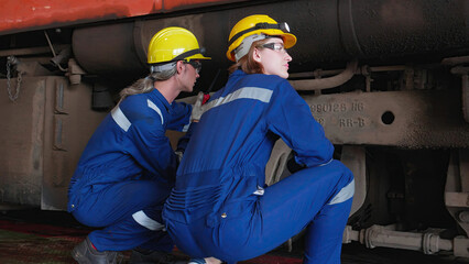 Fototapeta premium Team caucasian engineer maintenance train while speaking with talkie for command in station, team engineer inspect system transport, technician checking infrastructure, transportation and industry.