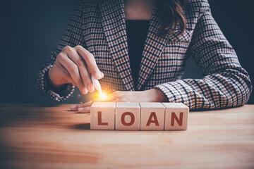 Businesswoman in checkered suit with wooden blocks cubes text "LOAN". Loan payment car and house, Interest and fees from loans are main revenue for banks, Business and finance concept.