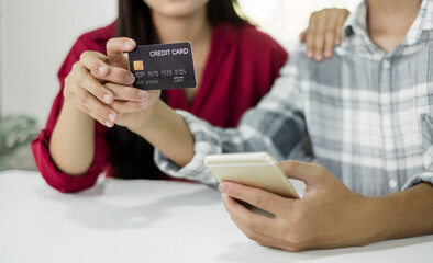 E-commerce Concept. Happy couple holding credit card enjoying doing online shopping and using laptop enter their card number in-app to purchase and payment in the internet store