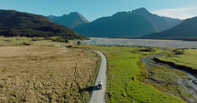 Scenic aerial view of campervan traveling through green plateau of rugged mountainous landscape exploring Isengard location from Lord of the Rings in Glenorchy, South Island of New Zealand Aotearoa