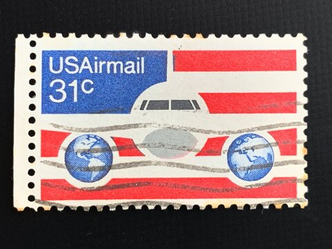 Bari, Italy - November 27, 2023. A 31 cent United States Airmail postage stamp, shows image of Plane and Globes on red white and blue background, circa 1976.