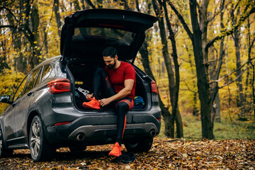 A runner is preparing for running in nature while sitting in his car.