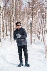 Fototapeta na wymiar happy Traveler with Sweater walking on snow covered forest in frosty weather. Winter Travel, Adventure, Exploring and Vacation concept