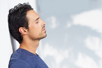 Thinking, calm and man profile by a white wall outdoor in the sun with freedom and ideas. Relax, peace and male person with mockup and summer with vitamin D, leaning and contemplating with outfit