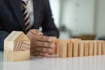 Real Estate Protection Risk Business Plan Human hands protect a row of falling wooden blocks like...