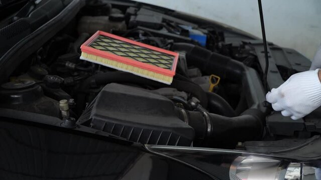 Man with dirty car air filter in hand, engine compartment. Car maintenance.