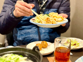 唐揚げを箸でつまむ中年男性の手元 © smile