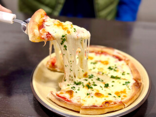 美味しそうなピザの1ピースを持ち上げるシーン © smile