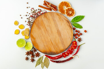 Wooden board surrounded by spices and cooking ingredients on white background