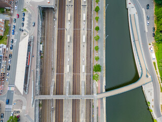 The image presents a top-down view of a railway station adjacent to a curving river, illustrating...