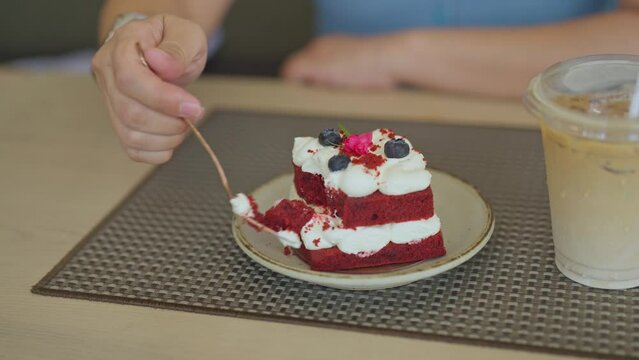 Close up image of hand woman eating blueberry cheesecake with fork on table in the cafe. Dessert cake for happy time enjoy eating.