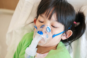 Sick little asian girl inhalation with nebulizer for respiratory treatment