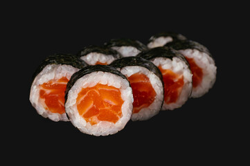 sushi roll with salmon isolated on black background.