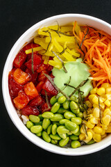 Hawaiian salmon poke bowl with rice on a black background